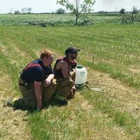 two firefighters crouching in grass