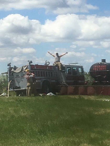 Two firefighters on top of large firetruck