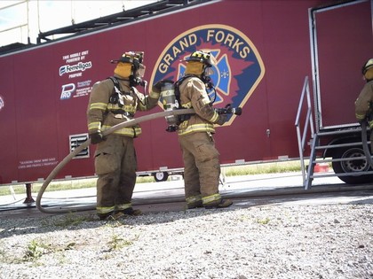 two firefighters holding fire fighting water hose 